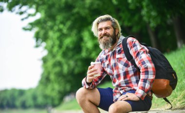 Sıcak kahve içiyorum. Çay ya da kahve iç. Bardaklı adam dışarıda. Nehir kenarındaki doğanın tadını çıkarıyorum. Sırt çantalı adam dinleniyor. İlham verici yakışıklı hippi. İlham. Dışarıda kahve içen bir adam var.