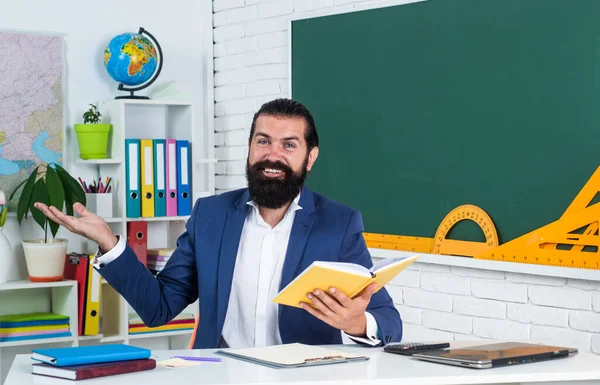 Счастливый бородатый взрослый хипстер мужчина в куртке держать книгу в школе для образования, чтение — стоковое фото