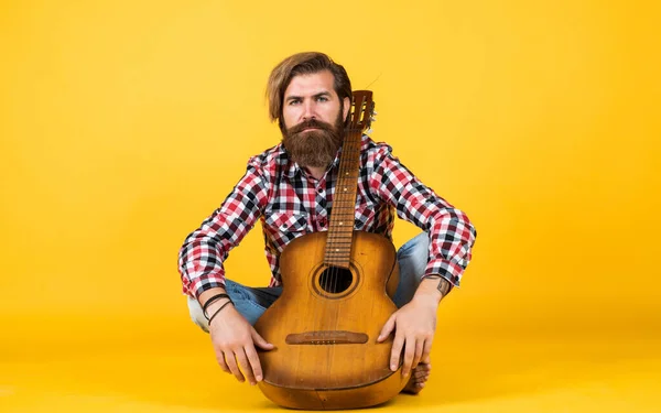 Bande acoustique. joyeux bel homme mature jouant de la guitare et souriant tout en étant assis sur fond jaune. Portrait d'un homme barbu heureux jouant de la guitare. un musicien solitaire — Photo