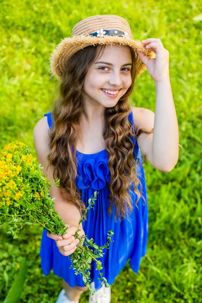 Naturlig skönhet. Glada barn håller blommor naturligt landskap. En liten flicka ler med solhatt på långt vågigt hår. Sommarmode och accessoarer. Skönhet och spa salong. Hudvård och hårvård — Stockfoto