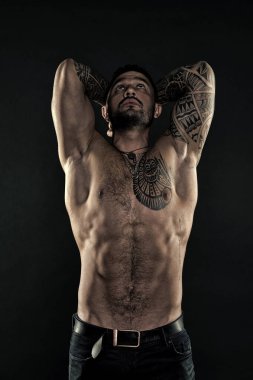 Erkek kaslarını esnetiyor. Vücut geliştirici pozu veren üst beden adamı. Erkek fitness modeli. Kot pantolonlu, çıplak vücutlu seksi bir sporcu. Gömleksiz kaslı adam. Erkek sağlığı ve güzelliği. Model, moda konsepti