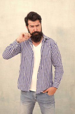 Çekicilik konsepti. Erkeklik ve erkek güzelliği. Sakallı ve bıyıklı hippi gömlek giyiyor. İyi giyimli bir adam. Zalim yakışıklı hippi gri duvar arkaplanı. Sakallı adam moda hipster tarzı