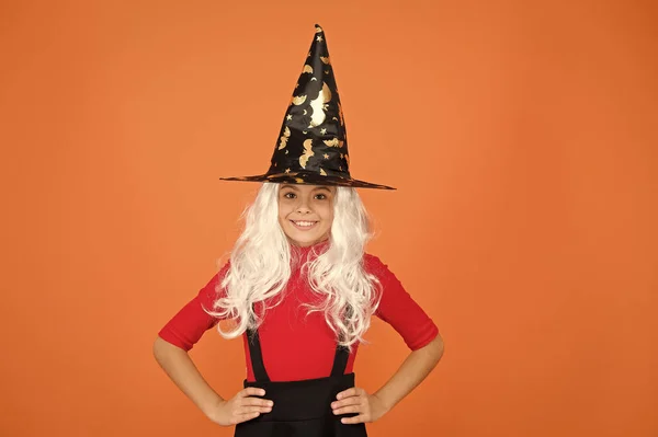 Enjoying great party. mystery witch. small child witch hat. trick or treat. supernatural charmer gray hair. kid orange background. happy halloween. magic fantasy. smiling small girl halloween party — Stock Photo, Image