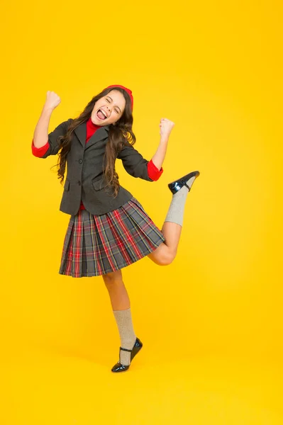 Щаслива маленька дівчинка в шкільній формі з виграшними жестами насолоджується святкуванням, стипендією — стокове фото