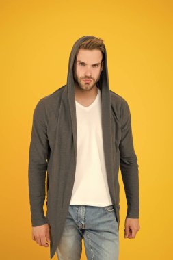 Yakışıklı ve sıradan biri. Yakışıklı adam sarı arka plan. Genç adam kapüşonlu sweatshirt giyiyor. Moda görünümlü yakışıklı bir manken. Moda ve tarz. Yakışıklı ve kendinden emin.