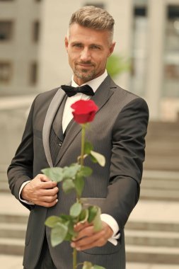 Çok modaya uygun bir görünüşü var. Damat kostümlü ve papyonlu. Adam sana gül verir. Kırmızı gül vermek için bir sebep. Smokin giyilecek yer. Sevgililer günüm için. Seni seviyorum sevgilim. Beyefendi Rose 'u yıldönümünde verdi.