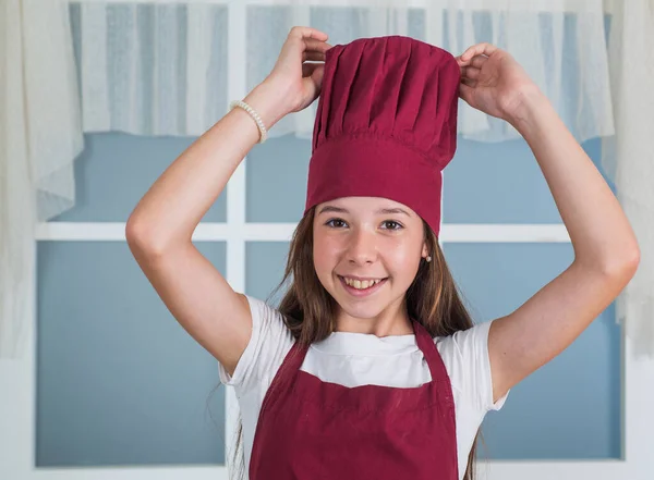 행복 한 아이들은 요리용 유니폼을 입습니다. 모자쓰고 앞치마입은 여자. 아이들은 부엌에서 요리를 합니다. 직업을 선택 한다. 부엌에 있는 작은 도우미. 요리와 요리. 행복 한 어린 시절 — 스톡 사진