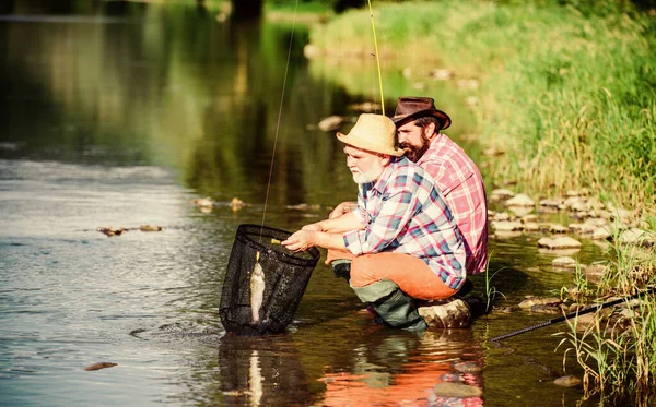 Sportvissen. Vissen en vangen. Twee mannelijke vrienden die samen vissen. vliegvissen hobby van mannen in geruit shirt. pensioenvisserij. Gelukkige vissers vriendschap. gepensioneerde vader en volwassen bebaarde zoon — Stockfoto