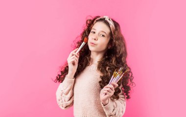 Cilt bakımı yapıyor. Kozmetik uygula. Genç cilt için cilt bakımı kozmetiği. Saç bandı takan mutlu kız makyaj için fırça tutuyor. Makyaj konsepti. Kusurları gizle. Mükemmel bir ton. Kozmetik salonu. Gençlik modası