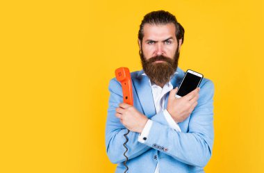 Dünyanızı seçin. O zaman ve şimdi. Olgun sakallı adam retro telefonda konuşuyor. Erkek, akıllı telefonu tutar. Teknolojiyi. Cep telefonuna karşı retro telefon. İş görüşmesi. Teknoloji gelişimi kavramı