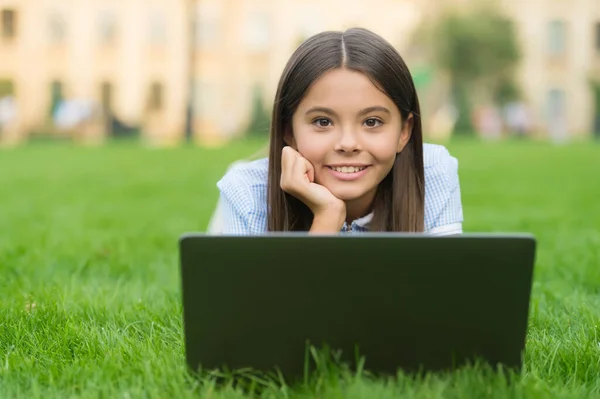 Niño feliz trabajando en el ordenador portátil. educación en línea. de vuelta a la escuela. adolescente uso de la computadora en la hierba verde en el parque. niño con cuaderno. nueva tecnología en la vida moderna. Estudia. Compras online — Foto de Stock