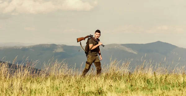 Homem brutal gamekeeper natureza paisagem fundo. Caminhando nas montanhas. Caçando conceito de hobby masculino. Regulação da caça. Hunter segura na espingarda. Belo dia para caçar. Hunter passar caça ao lazer — Fotografia de Stock