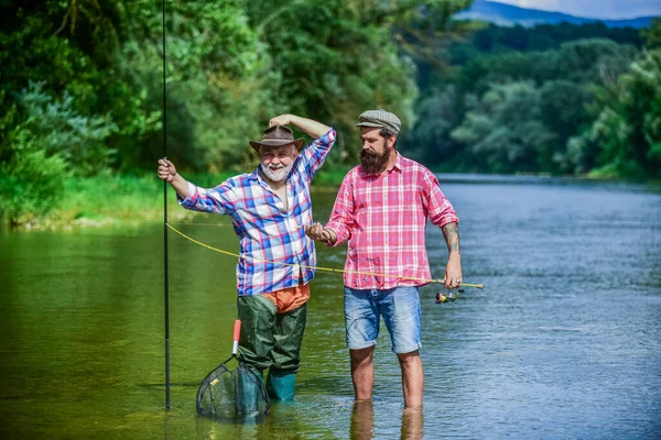 Legati insieme nell'amore. due pescatori felici con canne da pesca. weekend estivo. uomini maturi pescatore. padre e figlio pesca. hobby e attività sportive. Esche di trota. amicizia maschile. legame familiare — Foto Stock