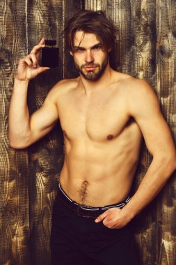 Beyaz sakallı seksi maço adam parfüm tutuyor.