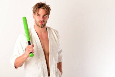 Adam elinde yeşil beyzbol sopasıyla beyaz kimonoyla poz veriyor..