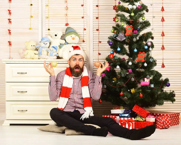 Homme à la barbe tient des boules de Noël dorées près des oreilles — Photo