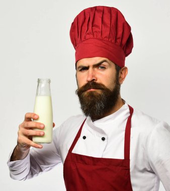 Sakallı bir adam beyaz arka planda süt şişesi tutuyor..