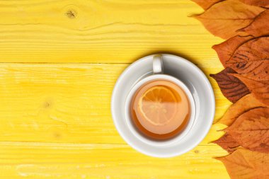 Kuru yapraklı çay fincanı sonbahar kompozisyonu oluşturur