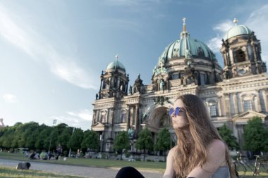 Berlin Katedrali 'nin önünde güneş kremi sürerek oturuyor.