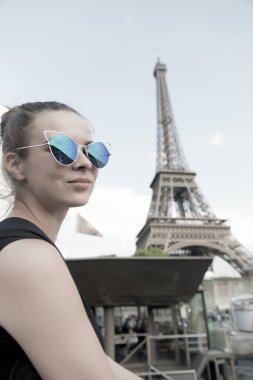 Paris, Fransa 'daki Eyfel Kulesi' nde seksi bir kadın pozu. Kadınlar güneşli bir günde şık güneş gözlüğü takarlar. Yaz tatilinde seyahat ve seyahat tutkusu. Moda görünümlü ve şehvetli bir kız.