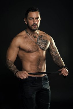 Seni cezalandıracağım. Deri kemerli manken. Dövmeli adam. Kaslı gövdeli sakallı adam. Kolu ve göğsü dövmeli bir sporcu. Spor ve spor. Ceza konsepti. Hükmeden erkek