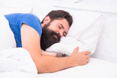Gömlekli, yakışıklı, olgun bir adam yatakta uyuyor, sağlıklı bir uyku çekiyor.
