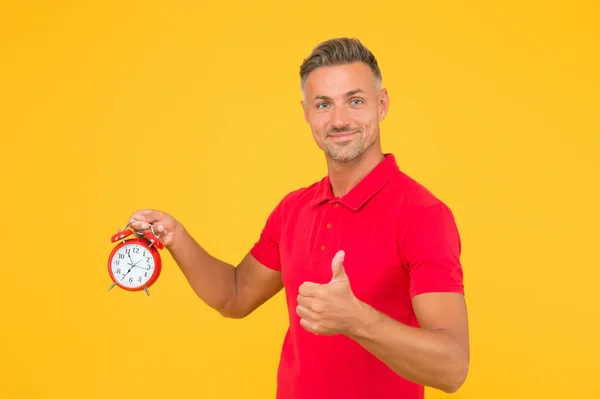 Il est toujours ponctuel. Un homme ponctuel tient un réveil montrant les pouces levés. Heureux d'être à l'heure. Heure précise. Ponctualité et chronométrage précis. Régulier comme une horloge — Photo