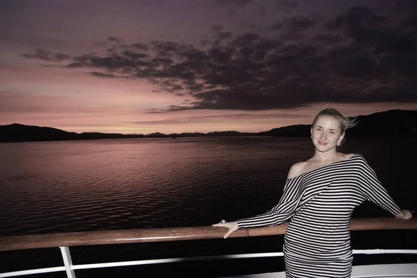 Mujer sonrisa en la cubierta del barco en el cielo dramático sobre el mar en Bergen, Noruega. Mujer feliz disfrutar de los viajes por mar en la noche. Puesta o salida del sol. Vacaciones de verano en el mar. Viaja por el agua. Aventura y vagabundeo — Foto de Stock