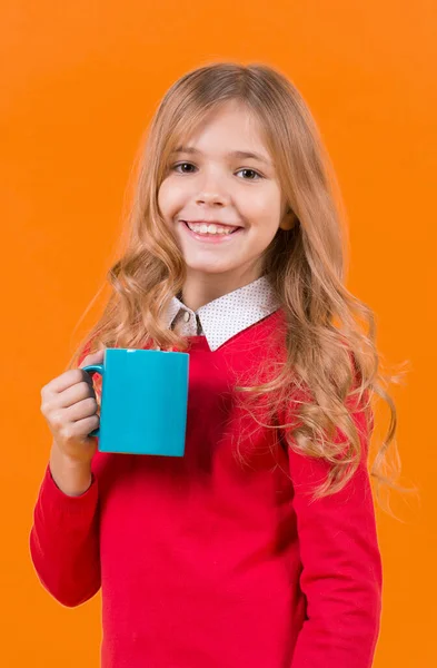 Детская улыбка с голубой чашкой на оранжевом фоне — стоковое фото