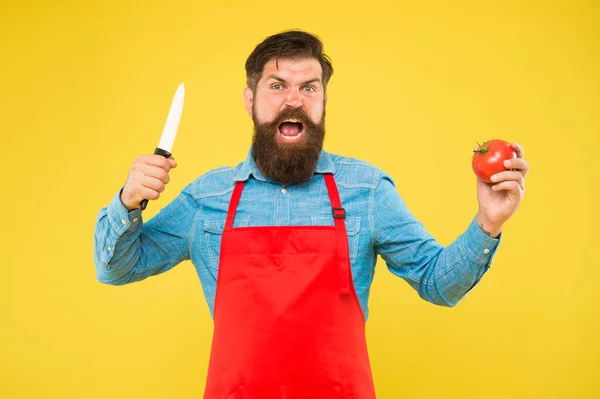 Hungry cook in apron hold tomato and knife for cooking healthy vegetarian food yellow background, hunger — Stock Photo, Image