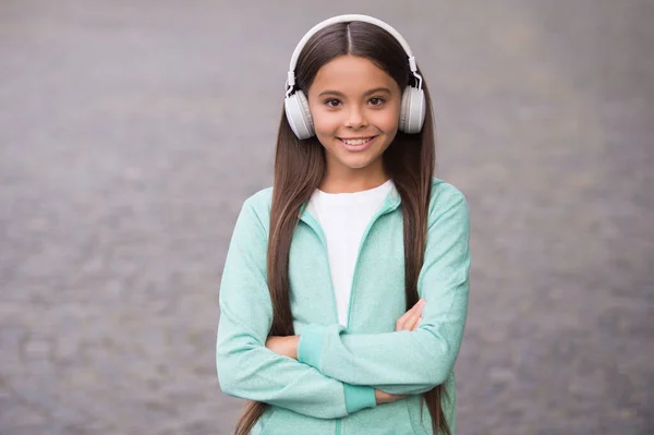Criança alegre usar fones de ouvido com música música ao ar livre apreciando melodia, de volta à escola — Fotografia de Stock