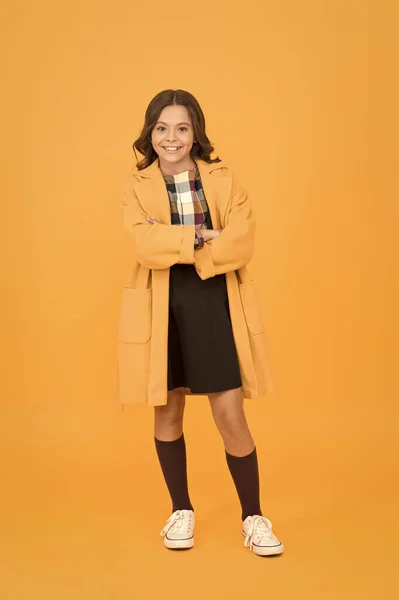 Get cozy in style this autumn season. Happy small girl wear comfortable fashion style. Little child with long brunette hair style smile orange background. Bringing some chic vibes to school style — Stock Photo, Image