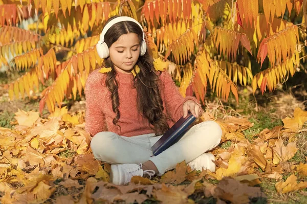 Self-study lesson on autumn nature. Small child practice listening on free time. Little girl listening to audio book in headphones. Listening course for beginners. Improving listening skills