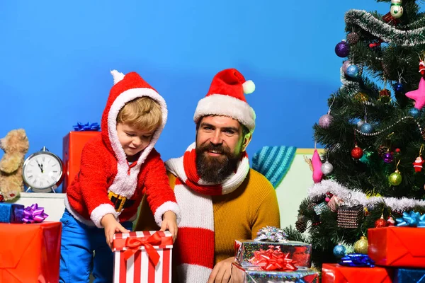 Weihnachtsmann und kleiner Helfer inmitten von Geschenkboxen am Weihnachtsbaum. — Stockfoto