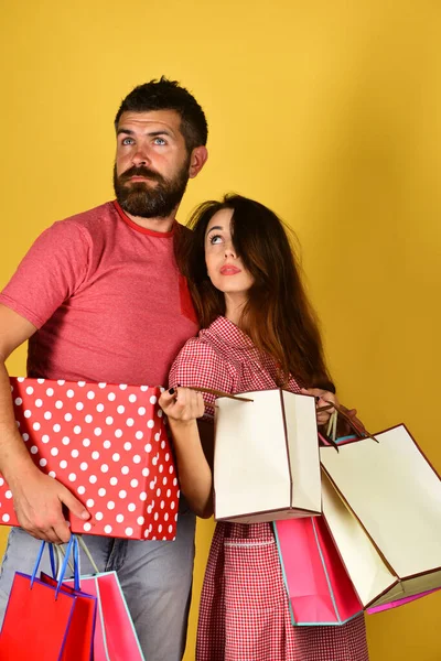 Pareja enamorada sostiene bolsas de compras sobre fondo amarillo. —  Fotos de Stock