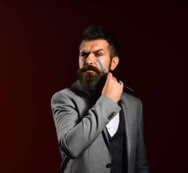Uzun sakallı adam jileti gözüne yakın tutuyor.