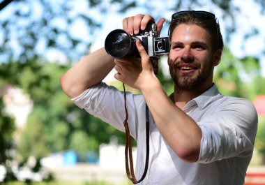 Gülen suratlı adam dışarıda fotoğraf çekiyor. Fotoğrafçı kamerayı tutuyor