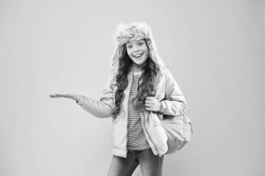 Parlak gelecek burada başlıyor. Artık sınav yok. Küçük mutlu kız okula geri döndü. Kış tatili. Çocuk sıcak kıyafetleri pembe arka plan. Mutlu çocuk kulaklı şapka. Sırt çantalı kız eve git.