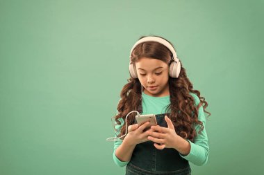 Çevrimiçi eğlence. Bedava müzik uygulamaları. Bedavaya dinle. Müzik hesabı aboneliği al. Küçük kız müzik dinler modern kulaklıklar ve akıllı telefon. Müzik konseptinin tadını çıkar Mükemmel sesin tadını çıkar