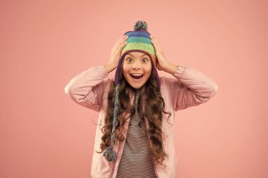 Neşeli bir ruh hali. Modaya uygun bir aksesuar. Kış mevsimi için çocuk şapkaları. Aksesuar kafa koruması. Sevimli küçük çocuk örülü aksesuar giyiyor. Moda aksesuarları ve pembe geçmişi olan sevimli küçük bir kız.