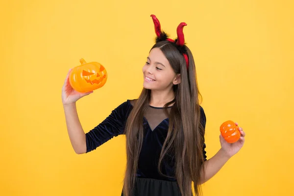 Enfant heureux porter costume cornes diable tenant citrouille pour créer Jack o lanterne sur fête d'Halloween, fête d'Halloween amusant — Photo