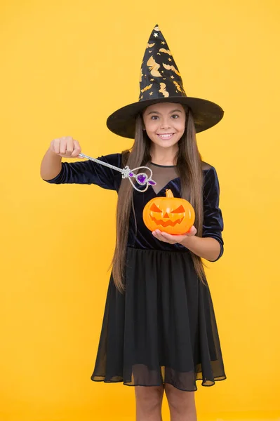 try a spell. kid create miracle with magic wand. carnival costume party. trick or treat. celebrate the holidays. jack o lantern. halloween witch girl. happy childhood. child in witch hat with pumpkin