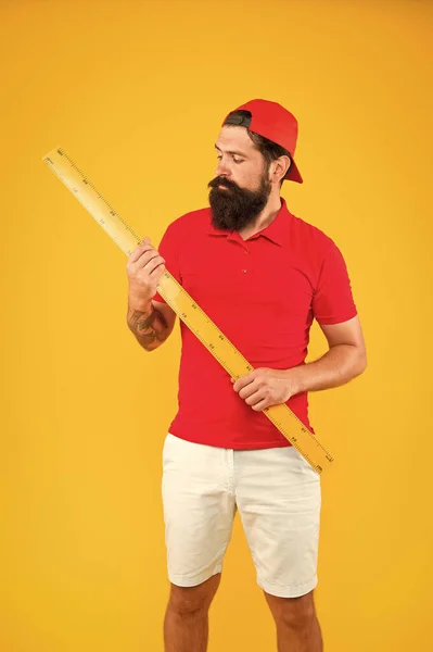 Meten met liniaal. Grootte meting. Meetlengte. Zware kleren. Studenten bestuderen stamdisciplines. Lange liniaal gereedschap apparatuur. Hoe zit het met jouw maat? Baard man met groot meetinstrument — Stockfoto