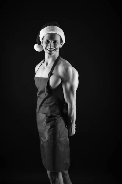 Cozinheiro sexy. O homem musculoso usa chapéu de Pai Natal. Fisiculturista em fundo preto. Férias de inverno. O desportista muscular celebra o Ano Novo. Espírito natalício. Tradição de Natal. Feliz Natal! — Fotografia de Stock
