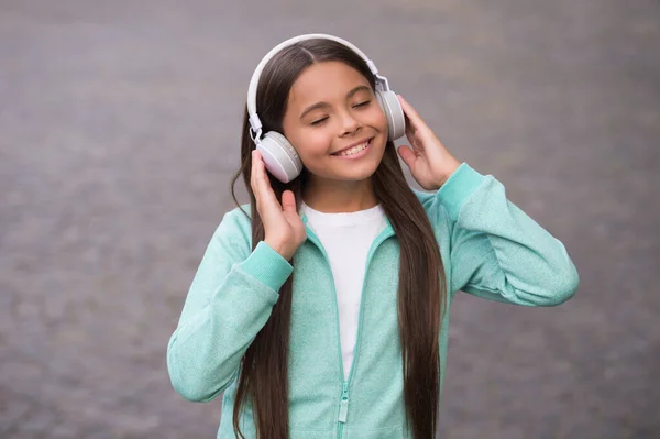 Alegre chica usar auriculares con música canción al aire libre disfrutando de la melodía, escuela educación en línea — Foto de Stock