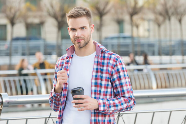 businessman walking outdoor. smart casual dressed person drinking coffee mug outdoor. Caucasian male resting in street on the way to work. Young man in checkered shirt. Enjoying beautiful morning