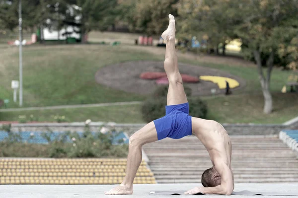 Hombre atlético haciendo asanas de yoga en el parque — Foto de Stock