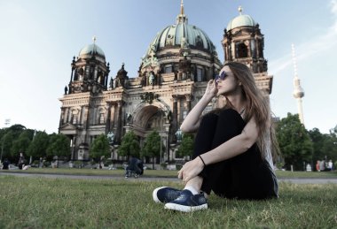 Berlin Katedrali 'nin önünde güneş kremi sürerek oturuyor.
