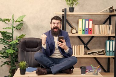 İnternette rahatla. Kişisel bakım. Rahatlama teknikleri. Zihinsel refah ve rahatlama. Adam sakallı yönetici resmi takım elbise lotus pozu rahatlatıcı. Uygulama akıllı telefonu. Oyun oynayın. Haberler iyi. Sosyal ağlar