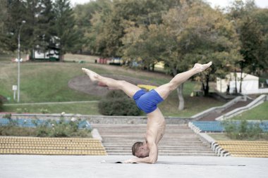 Atletik adam parkta yoga yapıyor.